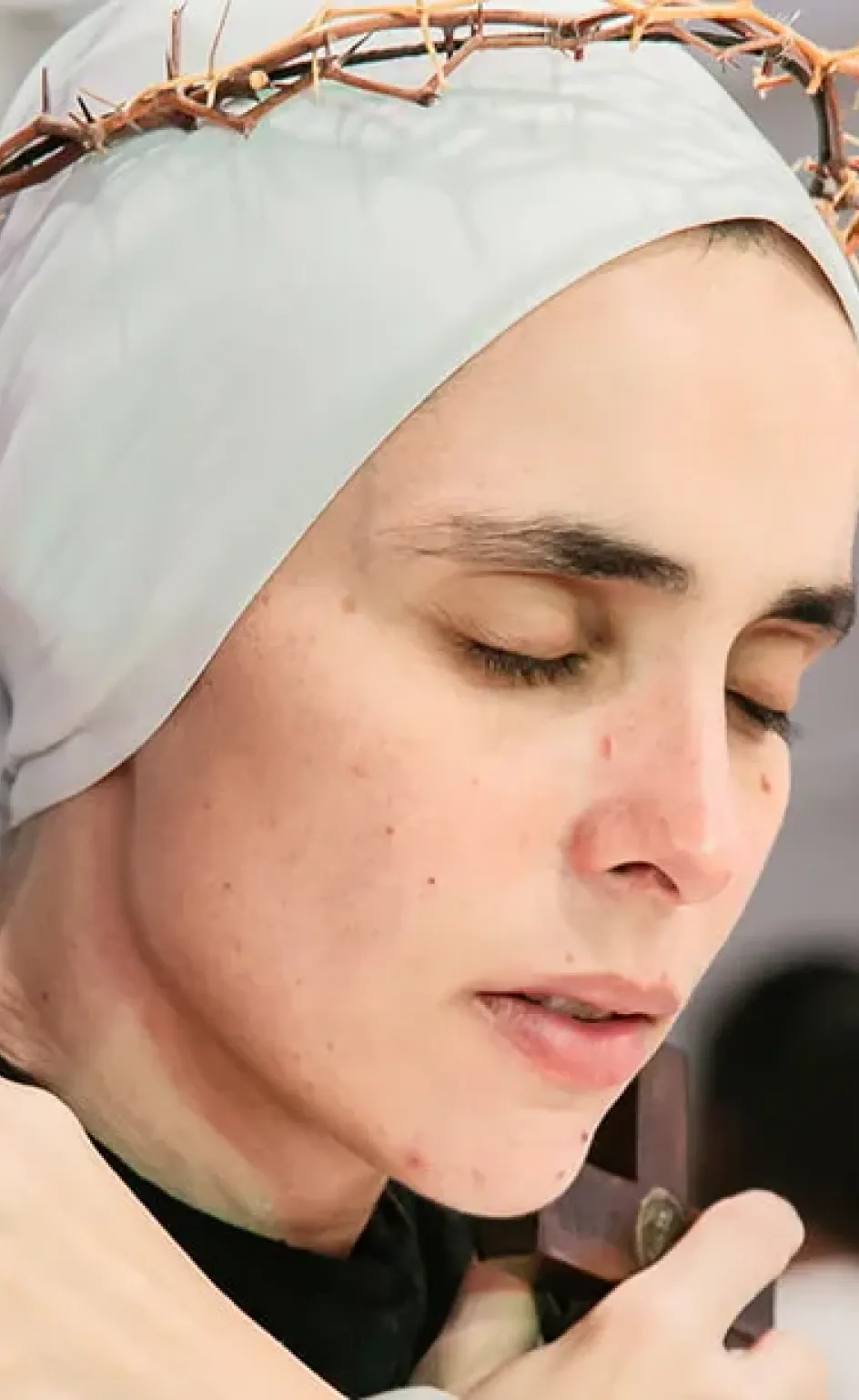Irmã do Instituto Hesed em oração, de olhos fechados, com uma coroa de espinhos